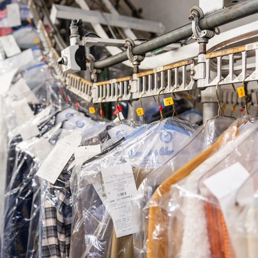 A row of dry cleaning racks with clothes hanging on them.