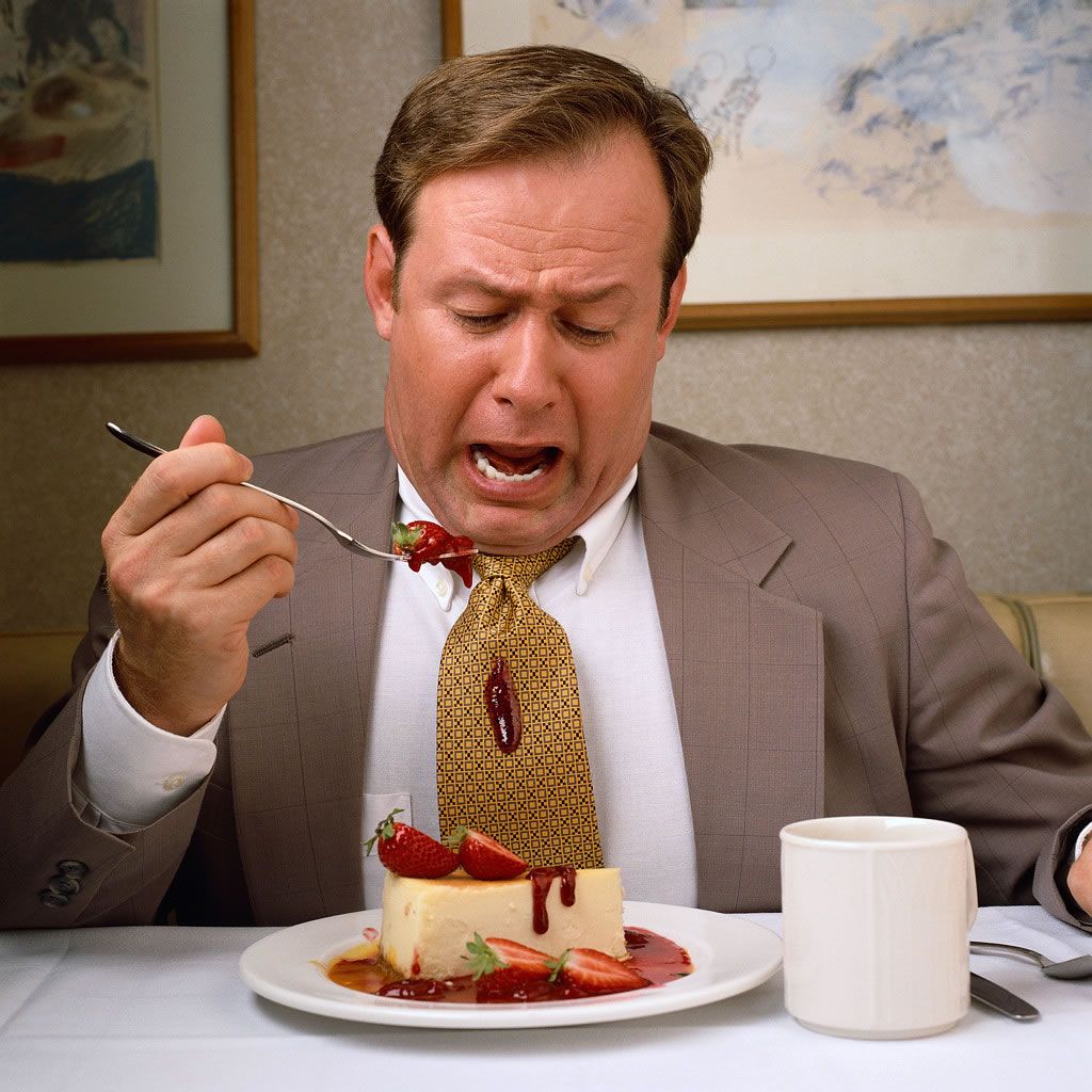 A man in a suit and tie eating cake.