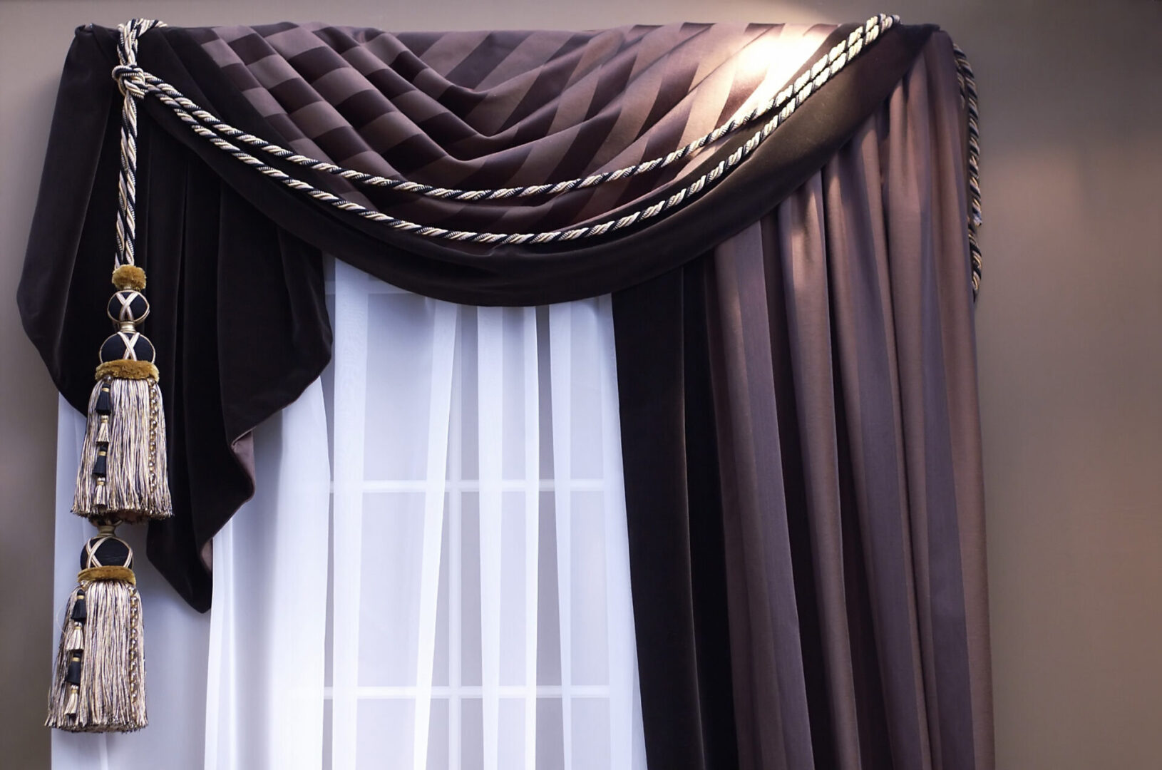 A window with curtains and drapes in the corner.